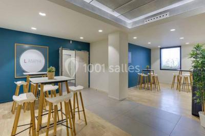 Terrasse avec des tables et chaises bleues, entourée de jardinières et d'une structure métallique végétalisée.