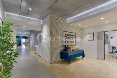 Terrasse avec des tables et chaises bleues, entourée de jardinières et d'une structure métallique végétalisée.