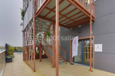 Terrasse avec des tables et chaises bleues, entourée de jardinières et d'une structure métallique végétalisée.