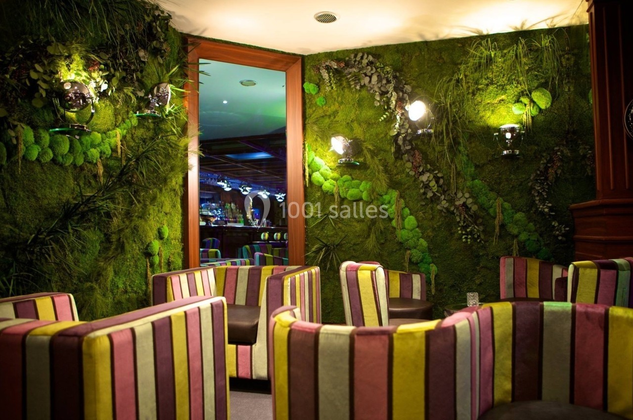 Salle avec des fauteuils rayés colorés, murs recouverts de végétation et éclairage tamisé.