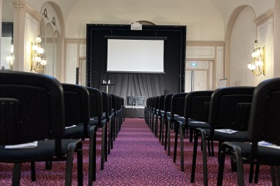 Salle avec des fauteuils rayés colorés, murs recouverts de végétation et éclairage tamisé.