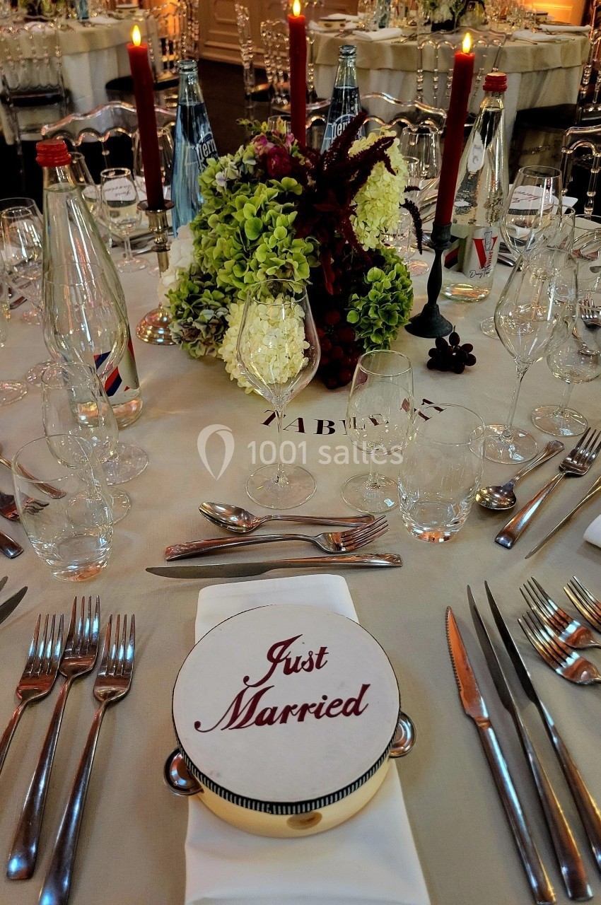 Table de réception élégamment dressée avec des couverts, des bougies, un centre de table floral et une assiette ’Just…