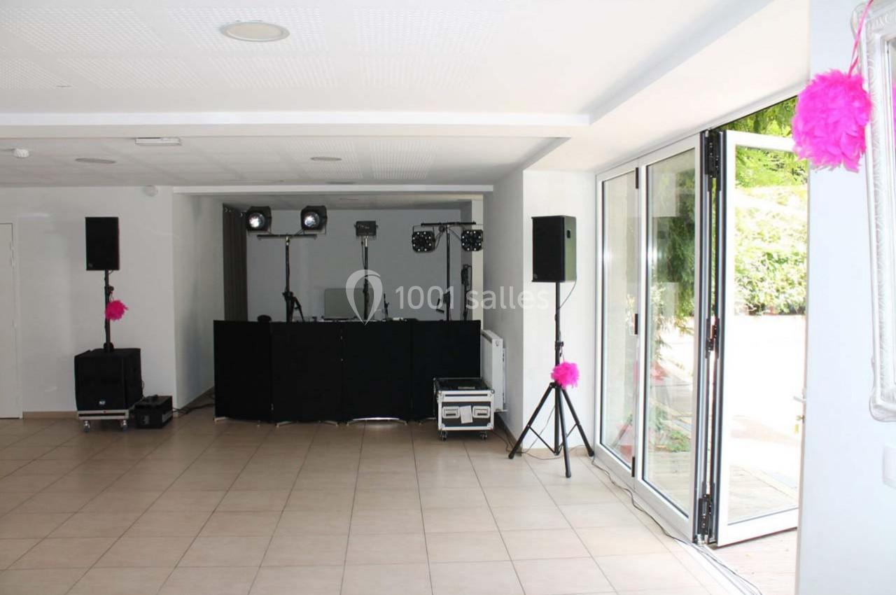 Salle lumineuse avec équipement de sonorisation et éclairage installé près de grandes portes vitrées ouvertes.