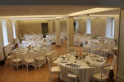 Jardin verdoyant avec un ruisseau traversant, entouré de grandes feuilles et d'arbustes fleuris, près d'une maison en pierre.