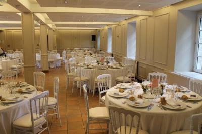 Jardin verdoyant avec un ruisseau traversant, entouré de grandes feuilles et d'arbustes fleuris, près d'une maison en pierre.