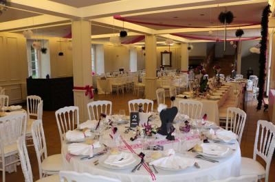 Jardin verdoyant avec un ruisseau traversant, entouré de grandes feuilles et d'arbustes fleuris, près d'une maison en pierre.