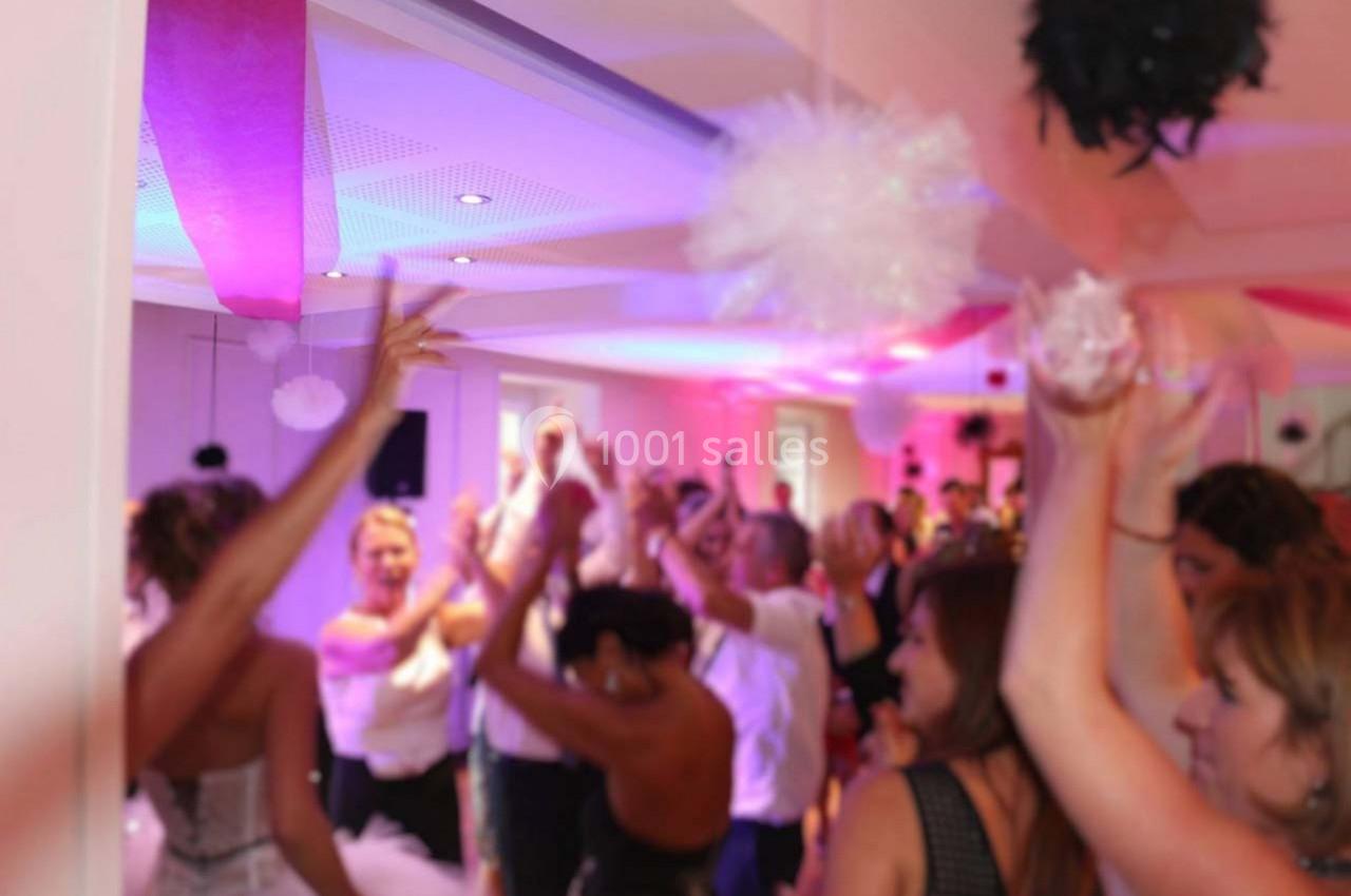 Groupe de personnes dansant et célébrant dans une salle décorée avec des lumières colorées et des guirlandes.