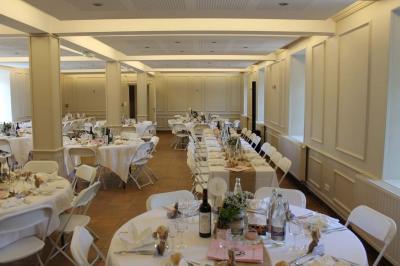 Jardin verdoyant avec un ruisseau traversant, entouré de grandes feuilles et d'arbustes fleuris, près d'une maison en pierre.