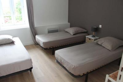 Jardin verdoyant avec un ruisseau traversant, entouré de grandes feuilles et d'arbustes fleuris, près d'une maison en pierre.