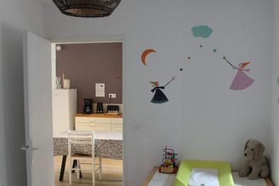 Jardin verdoyant avec un ruisseau traversant, entouré de grandes feuilles et d'arbustes fleuris, près d'une maison en pierre.