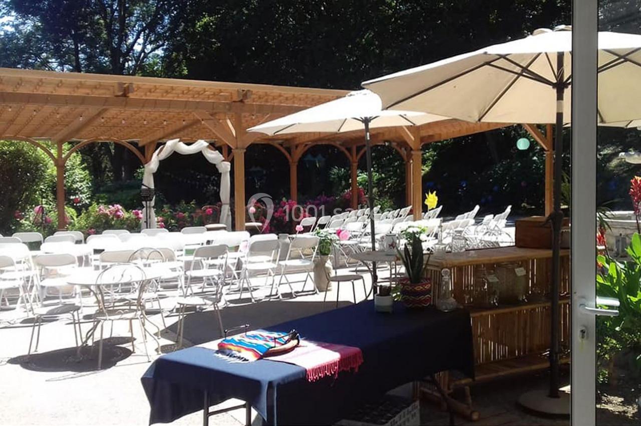 Terrasse aménagée avec des chaises blanches, une pergola en bois, des parasols et des décorations florales.