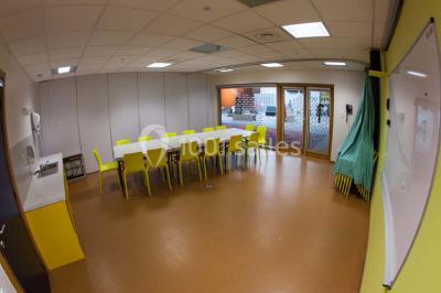 Un groupe de personnes rassemblé sous un grand parasol éclairé par des lumières violettes, dans un jardin de nuit.