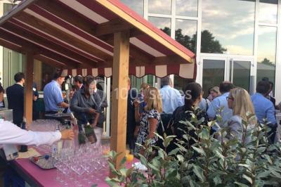 Un groupe de personnes rassemblé sous un grand parasol éclairé par des lumières violettes, dans un jardin de nuit.