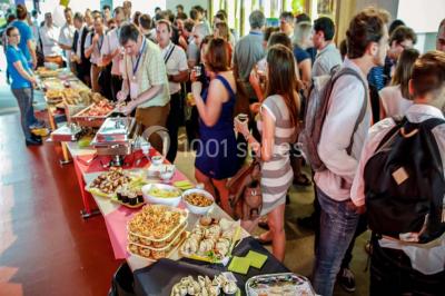 Un groupe de personnes rassemblé sous un grand parasol éclairé par des lumières violettes, dans un jardin de nuit.