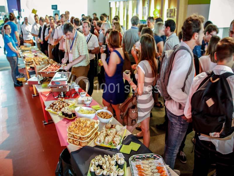 Groupe de personnes se servant à un buffet varié lors d'un événement dans une salle lumineuse.