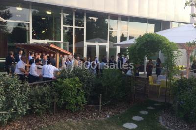 Un groupe de personnes rassemblé sous un grand parasol éclairé par des lumières violettes, dans un jardin de nuit.
