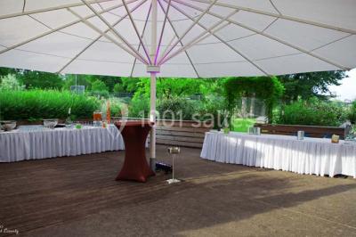 Un groupe de personnes rassemblé sous un grand parasol éclairé par des lumières violettes, dans un jardin de nuit.