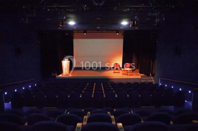 Un groupe de personnes rassemblé sous un grand parasol éclairé par des lumières violettes, dans un jardin de nuit.