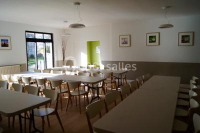 Salle de réunion avec des chaises disposées face à un écran de projection allumé, éclairage tamisé.