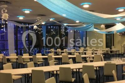 Vue intérieure d'une salle circulaire avec de grandes baies vitrées donnant sur la mer et un ciel partiellement nuageux.