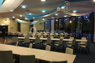 Vue intérieure d'une salle circulaire avec de grandes baies vitrées donnant sur la mer et un ciel partiellement nuageux.