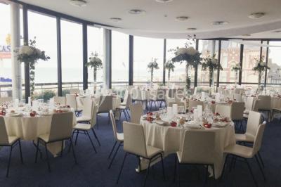 Vue intérieure d'une salle circulaire avec de grandes baies vitrées donnant sur la mer et un ciel partiellement nuageux.