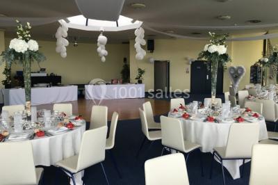 Vue intérieure d'une salle circulaire avec de grandes baies vitrées donnant sur la mer et un ciel partiellement nuageux.