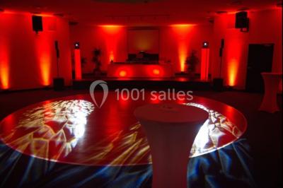 Vue intérieure d'une salle circulaire avec de grandes baies vitrées donnant sur la mer et un ciel partiellement nuageux.