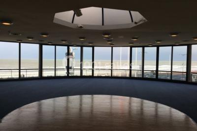 Miniature Location salle Villers-sur-Mer (Calvados) - Salle Panoramique Villers Sur Mer #7 Salle avec de grandes baies vitrées, tables dressées avec nappes orange, assiettes bleues et verres, vue sur un bâtiment…