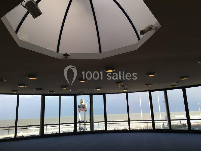 Location salle Villers-sur-Mer (Calvados) - Salle Panoramique Villers Sur Mer #10 Vue intérieure d'une salle circulaire avec de grandes baies vitrées donnant sur la mer et un ciel partiellement nuageux.