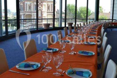 Miniature Location salle Villers-sur-Mer (Calvados) - Salle Panoramique Villers Sur Mer #14 Salle avec de grandes baies vitrées, tables dressées avec nappes orange, assiettes bleues et verres, vue sur un bâtiment…