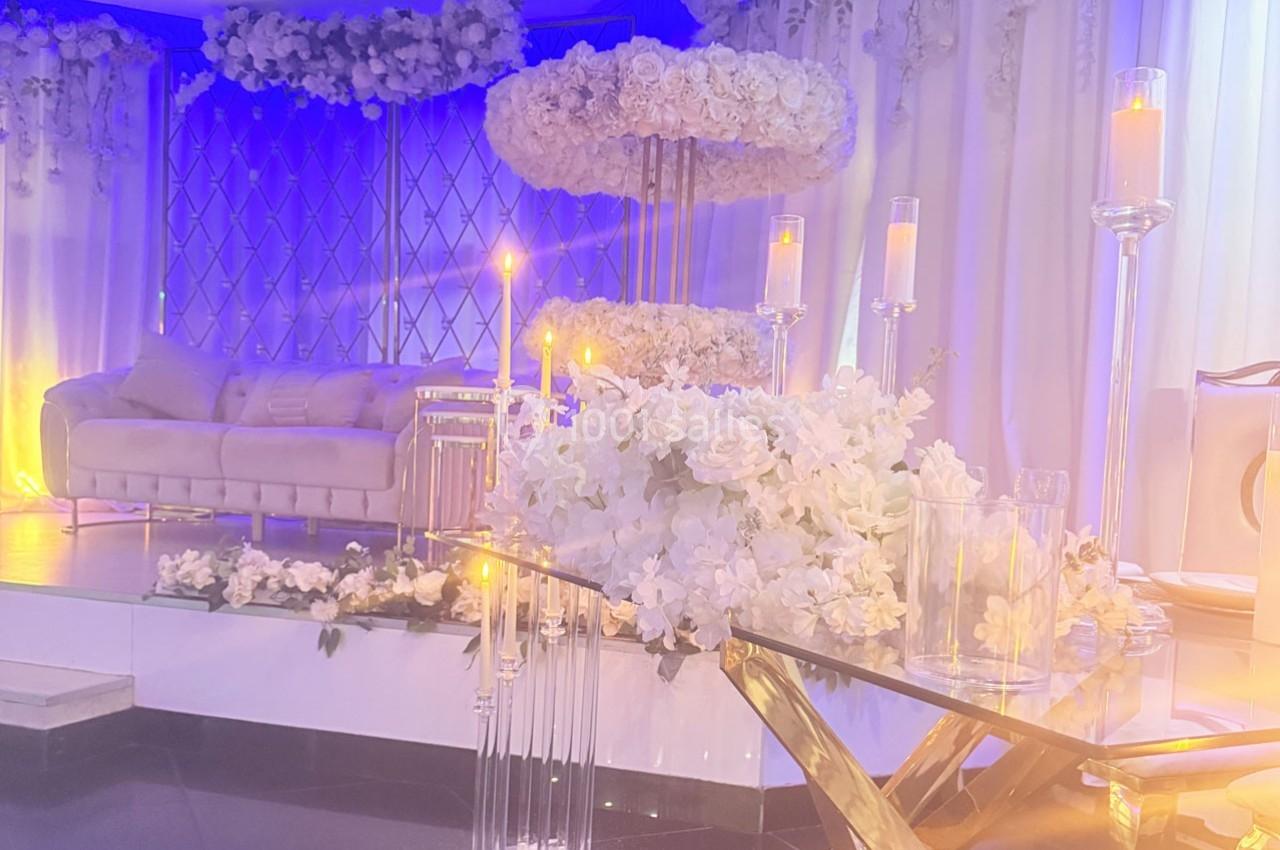 Décoration élégante avec des fleurs blanches, bougies et un canapé beige dans un espace lumineux et raffiné.