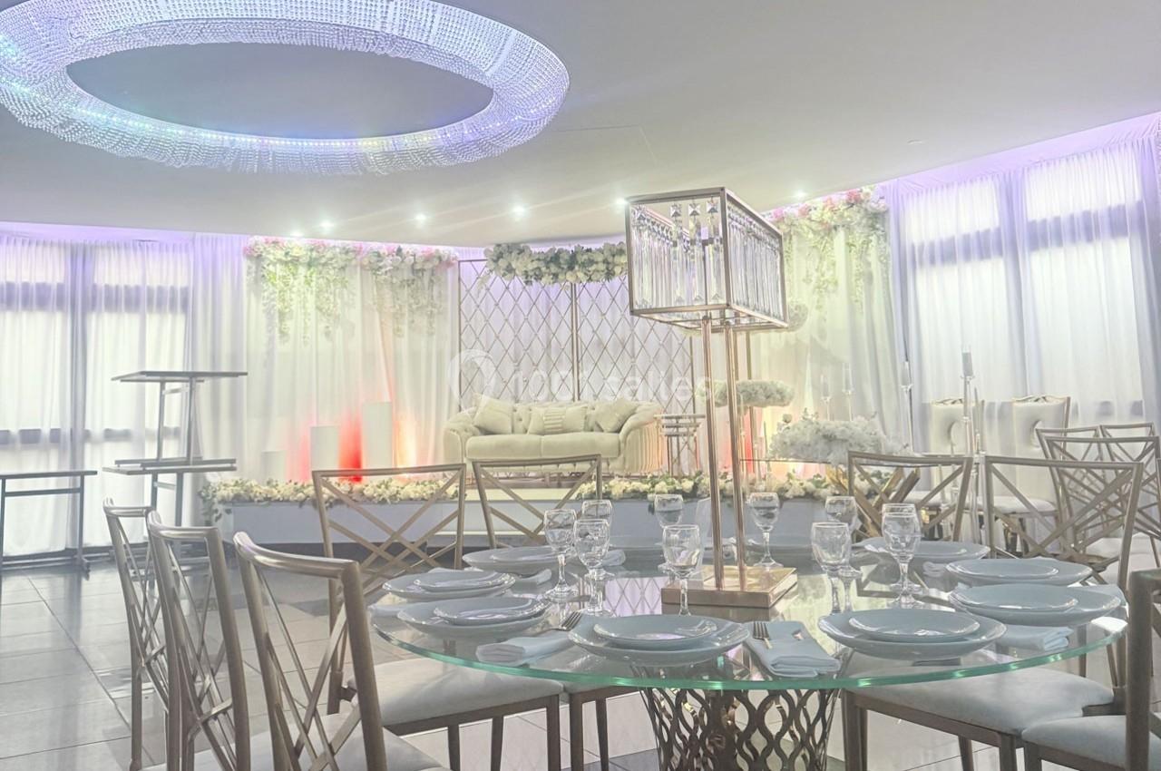 Salle de réception élégante avec table dressée, canapé décoré de fleurs et éclairage tamisé.