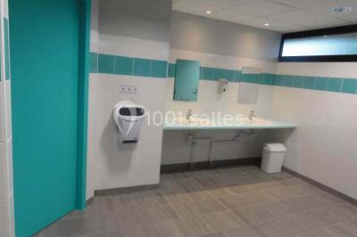 Cuisine avec un évier en inox, un plan de travail sombre, un réfrigérateur blanc et des murs bleus.