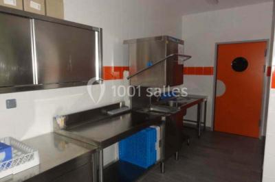 Cuisine avec un évier en inox, un plan de travail sombre, un réfrigérateur blanc et des murs bleus.