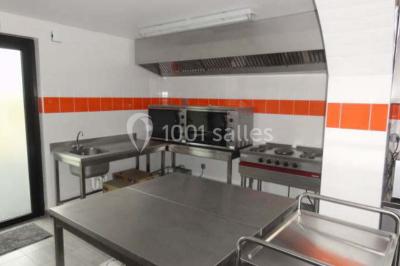 Cuisine avec un évier en inox, un plan de travail sombre, un réfrigérateur blanc et des murs bleus.