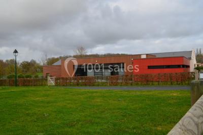 Cuisine avec un évier en inox, un plan de travail sombre, un réfrigérateur blanc et des murs bleus.