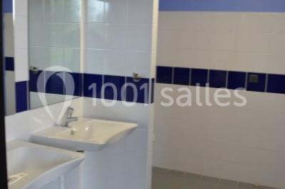 Cuisine avec un évier en inox, un plan de travail sombre, un réfrigérateur blanc et des murs bleus.