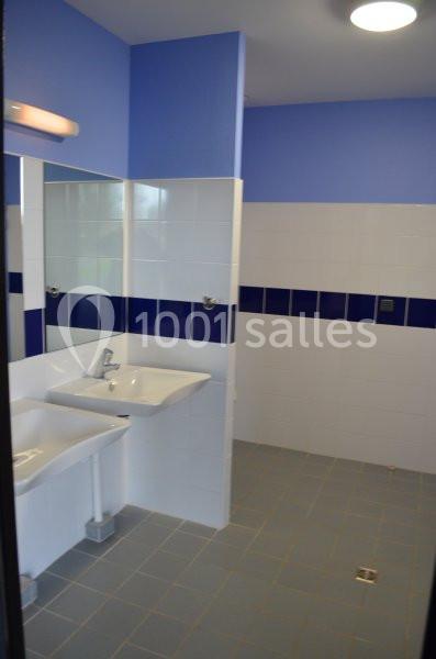 Salle de bain avec murs carrelés blancs et bleus, deux lavabos et un éclairage au plafond.