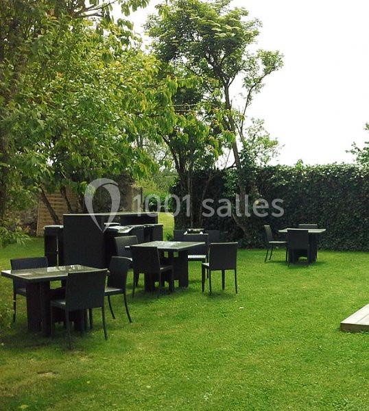 Mobilier de jardin noir disposé sur une pelouse verte, entouré d'arbres et de haies.