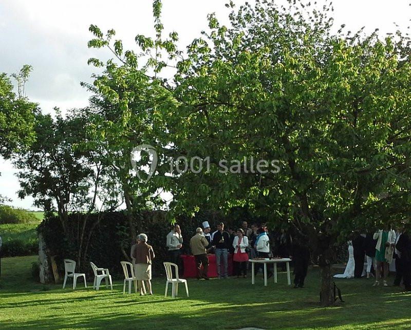 Un groupe de personnes rassemblé dans un jardin verdoyant près d'arbres et de chaises blanches.