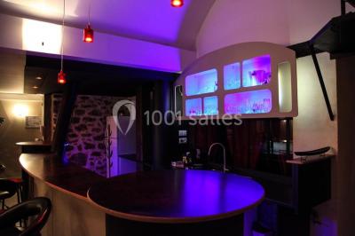 Comptoir en verre avec base en bois sculpté, entouré de portants métalliques avec des cintres noirs dans un espace moderne.