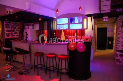 Comptoir en verre avec base en bois sculpté, entouré de portants métalliques avec des cintres noirs dans un espace moderne.