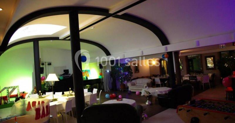 Salle de réception décorée avec des tables dressées, des lumières colorées et des éléments festifs.