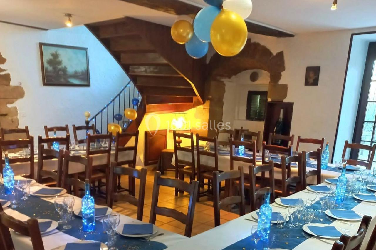 Salle de réception décorée avec des ballons bleus et jaunes, tables dressées avec nappes bleues et vaisselle élégante.