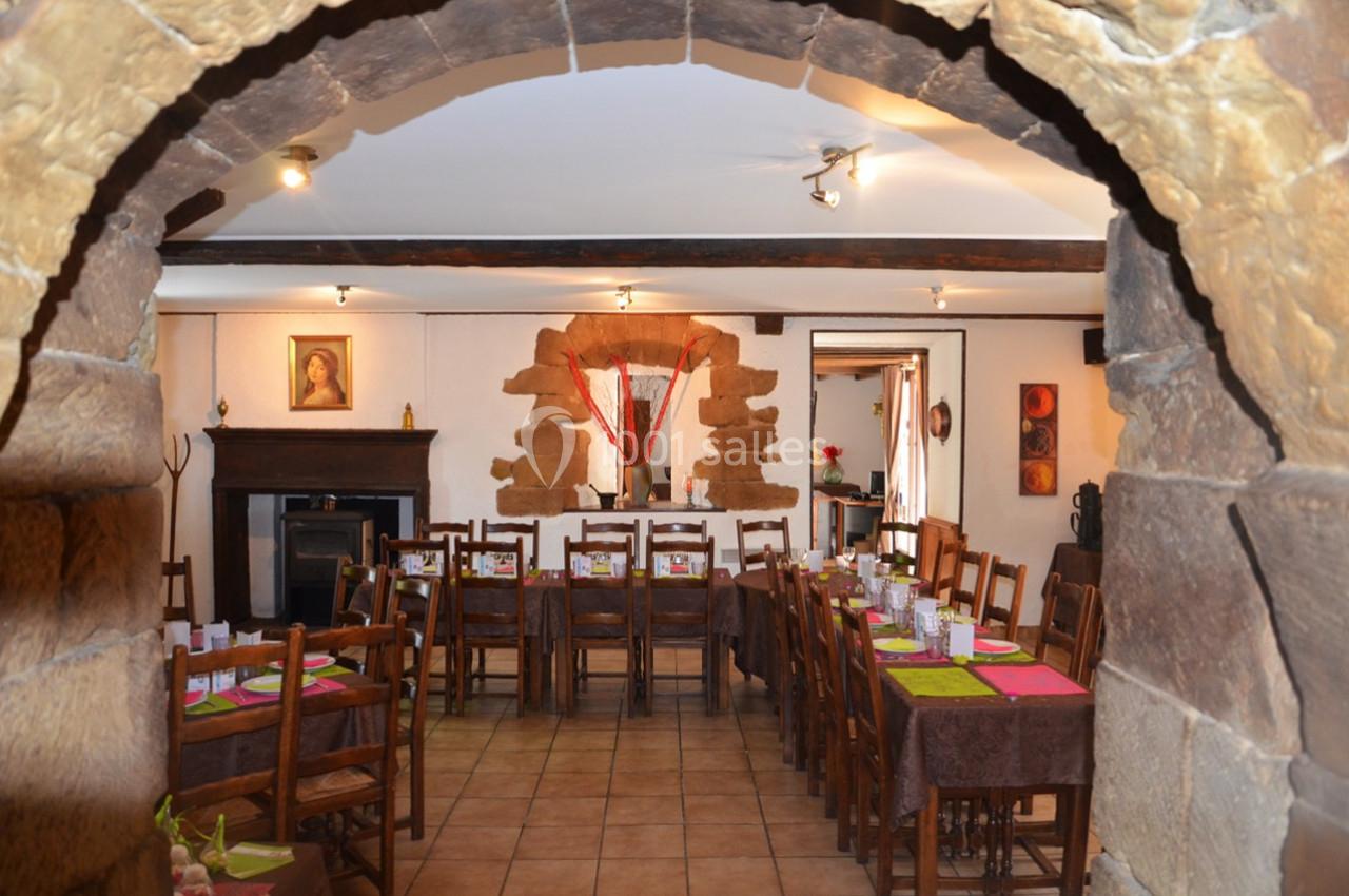 Salle à manger rustique avec tables en bois dressées, murs en pierre et décorations chaleureuses.