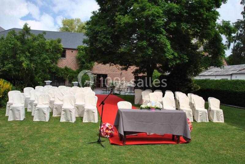 Disposition de chaises blanches et d'une table sur une pelouse, préparées pour une cérémonie en extérieur.