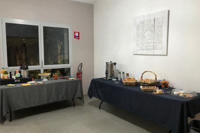 Buffet avec boissons, viennoiseries, fruits et condiments disposés sur deux tables dans une salle lumineuse.