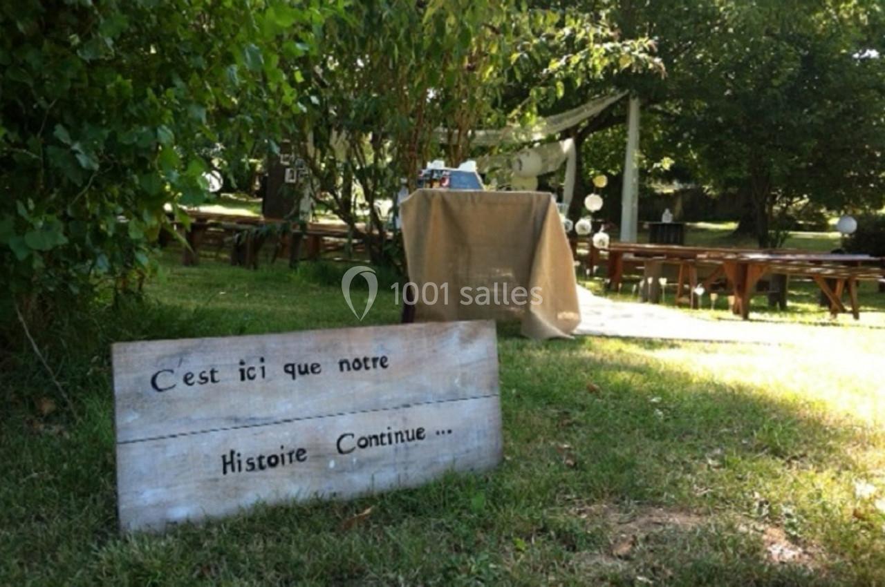 Panneau en bois avec l'inscription ’C'est ici que notre histoire continue’ dans un jardin décoré pour un événement.