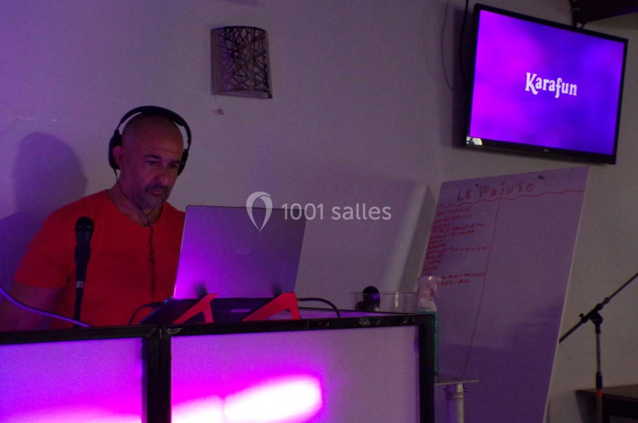 Un homme avec un casque anime une session de karaoké devant un ordinateur, avec un écran affichant ’Karafun’.